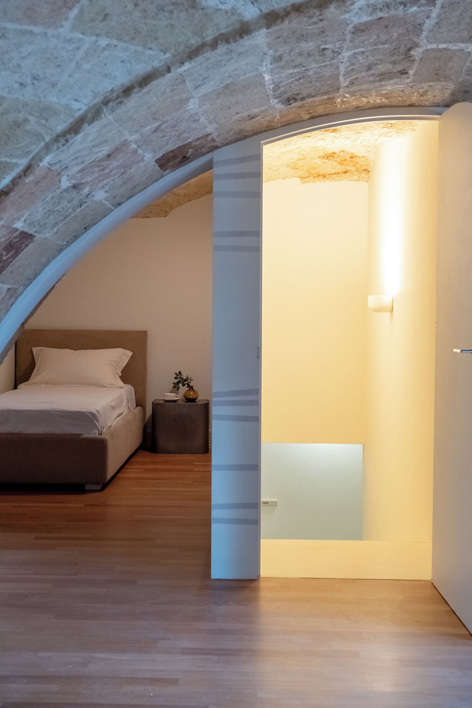 Ein Schlafzimmer mit einem Bett, einem Nachttisch und einer Wandleuchte.