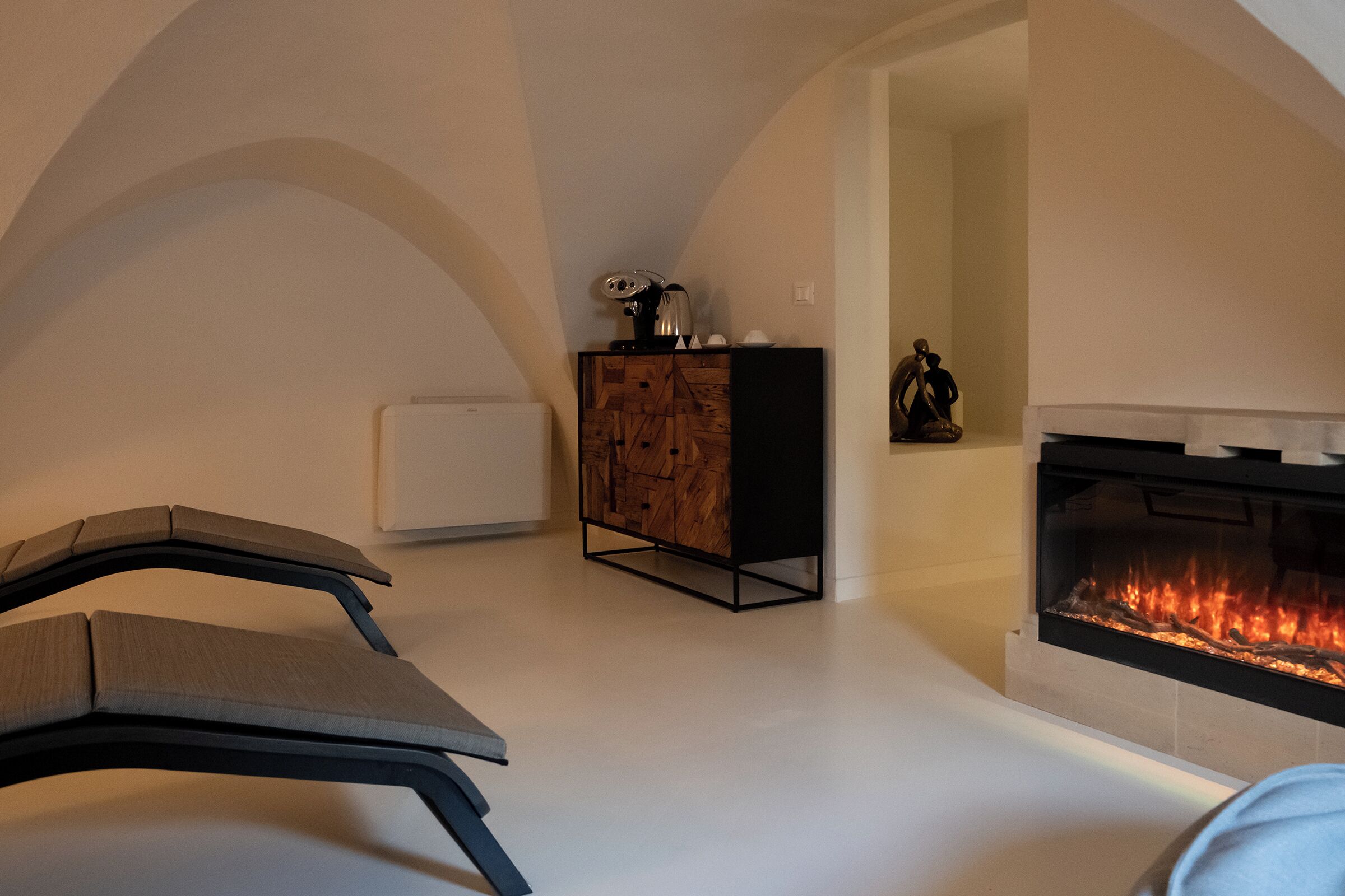 A modern living room with a fireplace, a sofa, a cabinet, and a radiator.