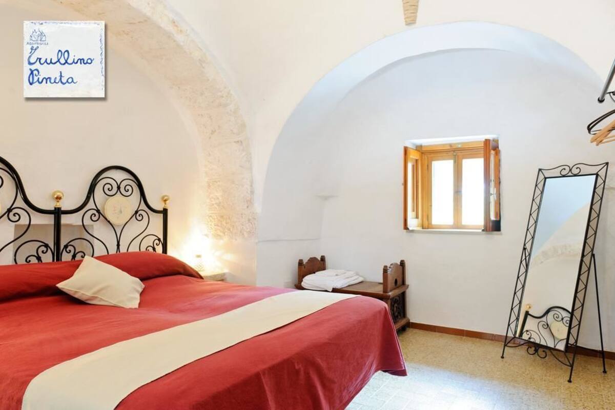 A bedroom with a bed, a mirror, a window, and a sign on the wall.