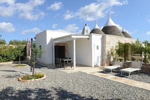 A modern building with a white exterior, a covered patio area, and a stone structure with conical roofs. - Allegroitalia Trulli Ostuni (Ostuni)