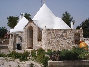 A stone building with a conical roof, a small entrance, and a staircase leading up to it. - Allegroitalia Trulli Ostuni (Ostuni)