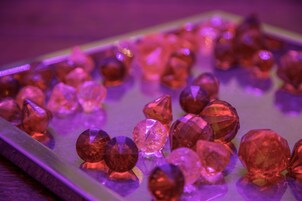 A collection of variously shaped and sized gemstones on a reflective surface.