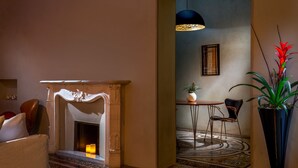 A cozy room with a fireplace, a dining table with chairs, a potted plant, and a hanging light fixture.