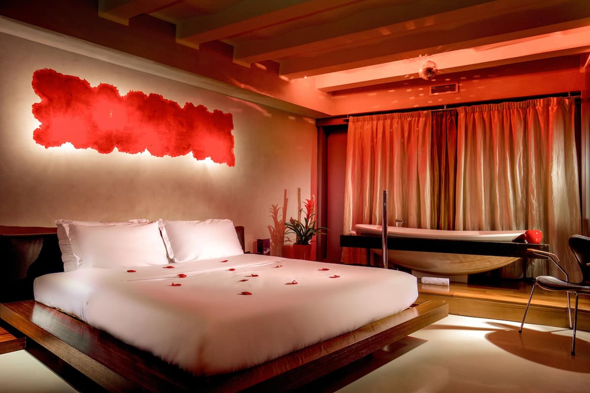 A modern hotel room with a large bed, a desk, and a chair.