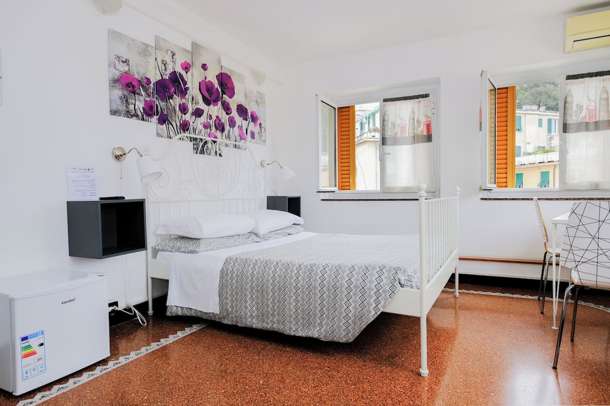 A bedroom with a bed, a desk, and a radiator.