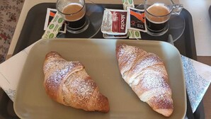 Una bandeja con dos croissants y dos tazas de café, junto con sobrecitos de chocolate Nocita.