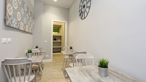 A dining area with a wooden table and chairs, a clock on the wall, and a decorative wall piece. - Capricci Romani (Rome)