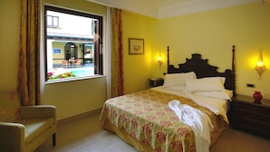 A hotel room with a bed, a chair, a window with curtains, and a view of the outside. - Grand Hotel Arciduca (Lipari)