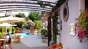 An outdoor patio area with wicker furniture, a pool, and potted plants. - Grand Hotel Arciduca (Lipari)