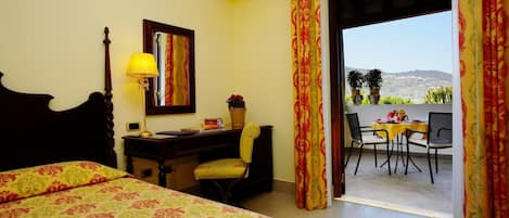Una habitación de hotel con cama, escritorio, silla y balcón con mesa y sillas.