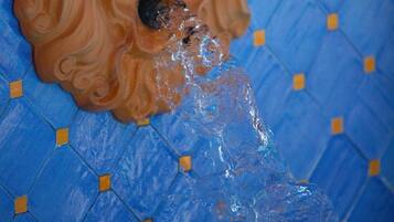 A carved wooden lion head sculpture on a blue tiled floor with a geometric pattern.