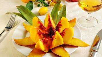 A plate of sliced mango with a glass of juice and a fork on a table.