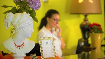 Un espace d’accueil agrémenté d’un buste sculpté en blanc, d’un menu encadré et d’un vase contenant des fleurs violettes.