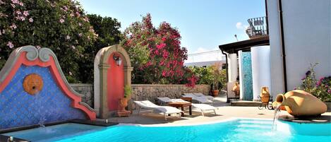 A swimming pool with lounge chairs and a decorative fountain.