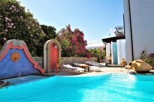 Una piscina con sillas de descanso y una fuente decorativa.