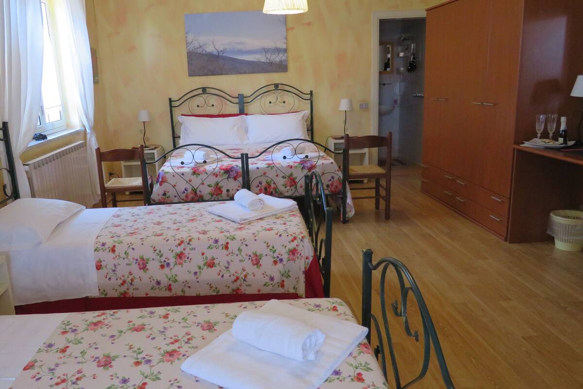 A hotel room with two beds, a wooden floor, a wooden wardrobe, and a painting on the wall.