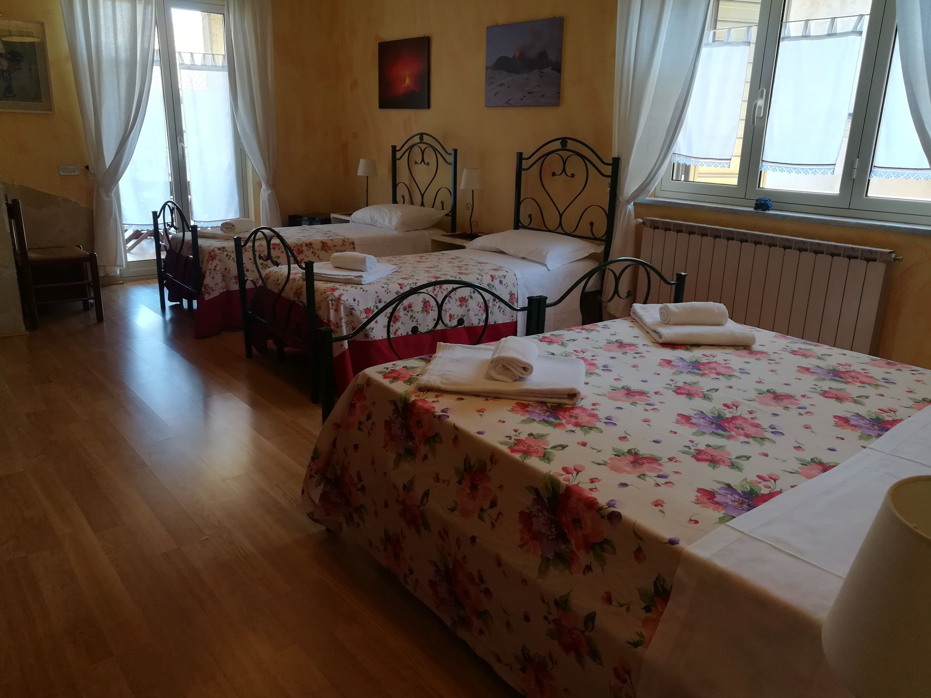 A hotel room with two beds, a chair, a table, and a window with curtains.