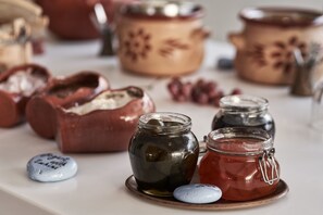 A table with jars of preserves and a ceramic pot. - Kivo Art & Gourmet Hotel (Skiathos)