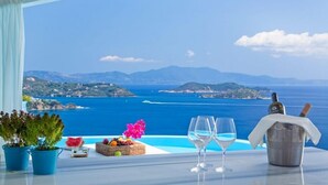 Une table avec vue sur la mer, une bouteille de champagne et un panier de fruits.