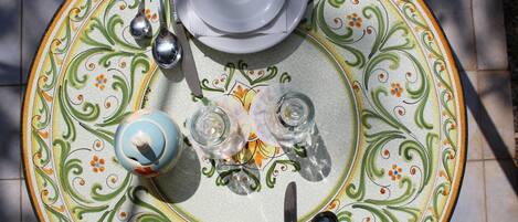 Una mesa servida con platos, cubiertos, vasos y una tetera.