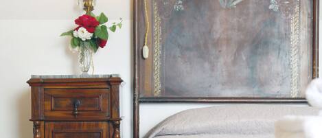 A bedroom with a wooden headboard, a bedside table with a vase of flowers, and a neatly made bed.