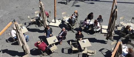 Un café al aire libre con mesas y sillas dispuestas sobre un área pavimentada.
