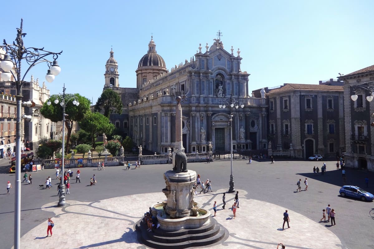 A spacious public square with a central fountain, surrounded by historic buildings with classical architecture.