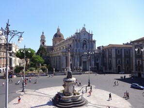 A spacious public square with a central fountain, surrounded by historic buildings with classical architecture.