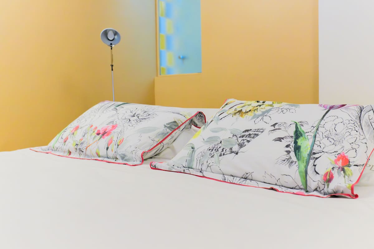 Una cama con almohadas de estampado floral y una lámpara de pie.