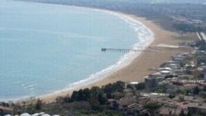 A coastal view with a beach, a pier extending into the sea, and a residential area with houses and greenery. - Villa San Giacomo (Scerni)