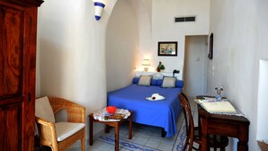 A small, cozy room with a bed, a chair, a table, and a wooden cabinet. - La Casa sul Mare (Procida)