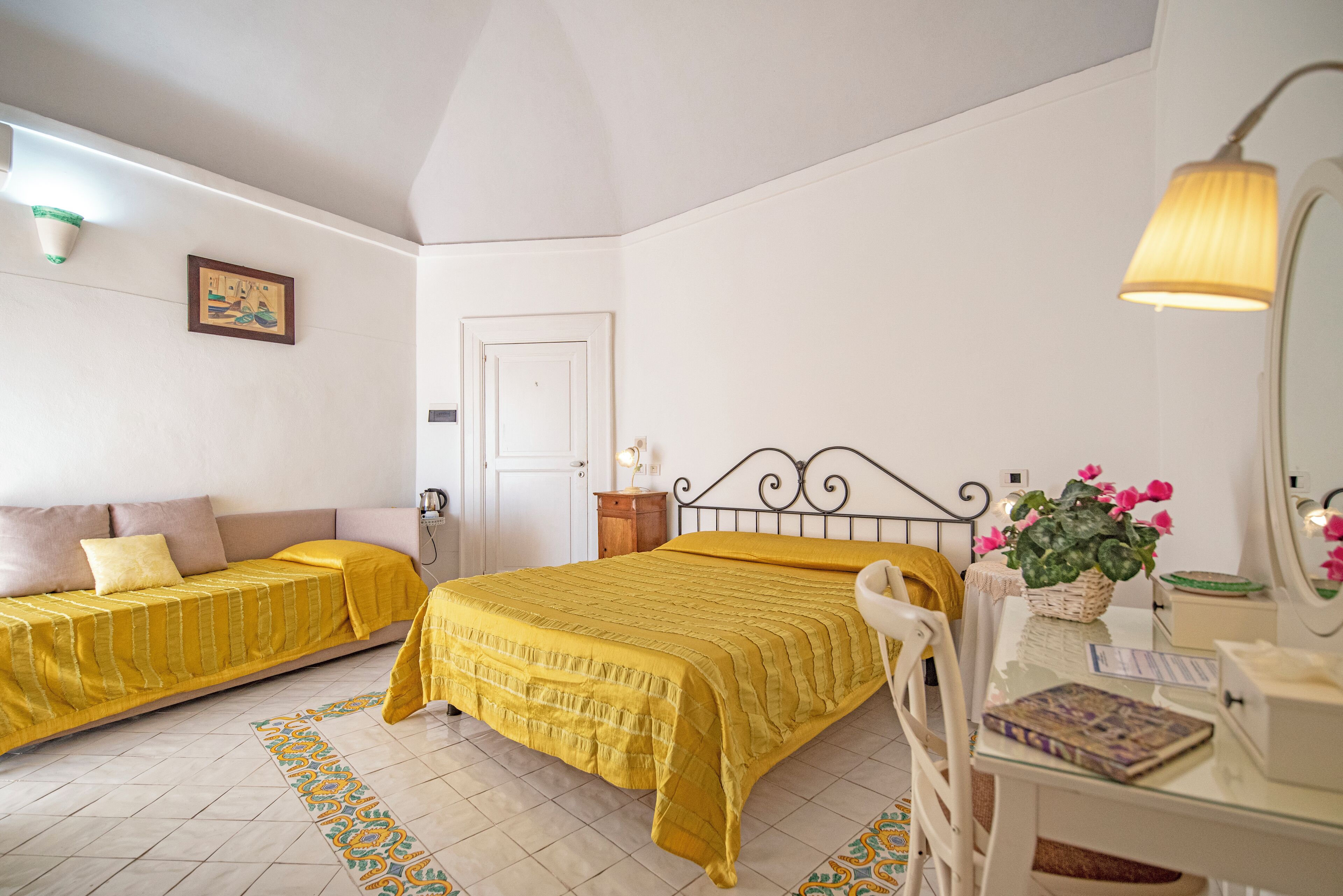 A bedroom with a bed, a bedside table, a chair, a desk, and a lamp.