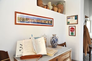 Una habitación con una mesa de madera, un jarrón, un cuadro enmarcado y diplomas en la pared.
