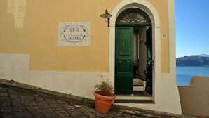 A hotel entrance with a green door, a sign above the door, and a potted plant in front. - La Casa sul Mare (Procida)
