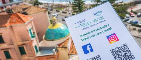 A sign for Hotel Baia Verde with a QR code, Facebook, and Instagram icons.