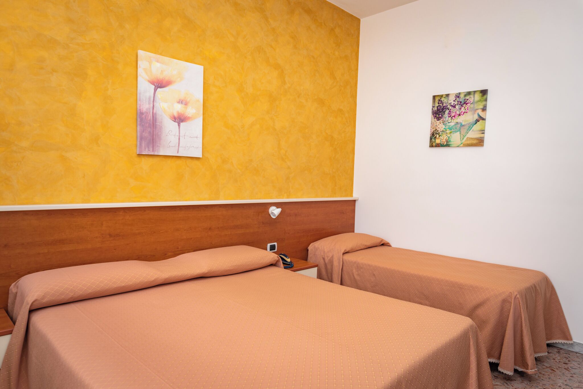 Una habitación de hotel con dos camas, un cabecero de madera y dos obras de arte colgadas en la pared.