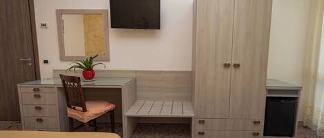 Une chambre d’hôtel équipée d’un bureau, d’une chaise, d’une armoire, d’une télévision et de deux lits.