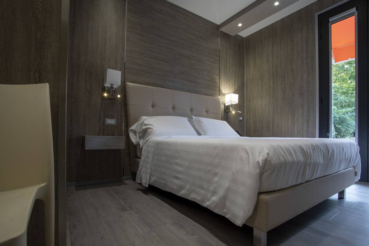 Une chambre à coucher moderne avec un grand lit, des murs recouverts de panneaux en bois et une table de chevet avec une lampe.