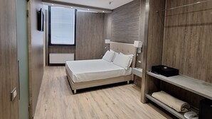 A modern bedroom with a bed, a vanity, and a walk-in closet.