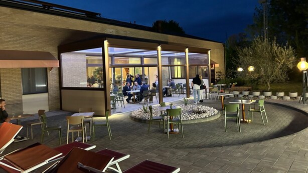 An outdoor patio area with tables and chairs, a covered seating area, and a brick wall.