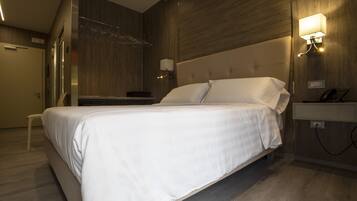 Ein modernes Hotelzimmer mit einem großen Bett, einem Nachttisch, einer Wandlampe und einer Wandverkleidung aus Holz.
