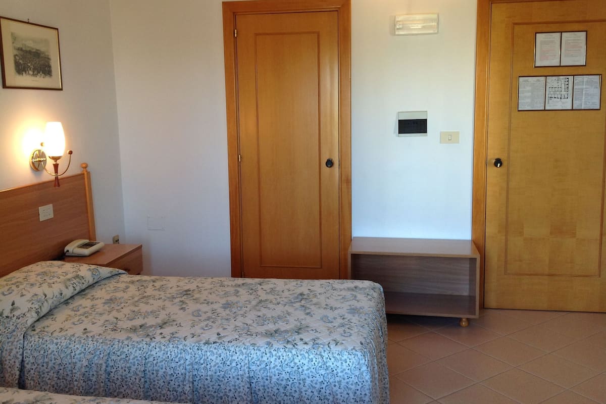 Un dormitorio con cama, mesita de noche, lámpara y dos puertas.
