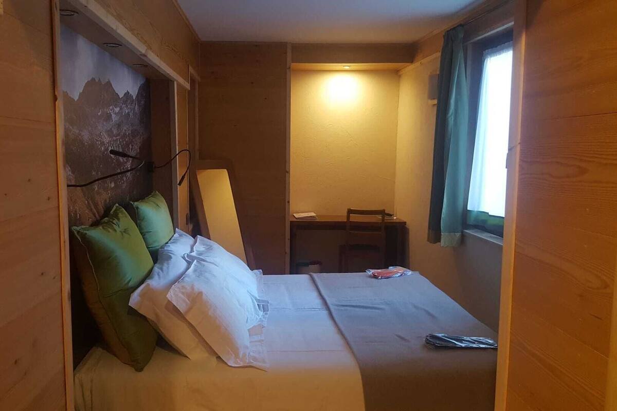 Una habitación pequeña con cama, escritorio y silla.