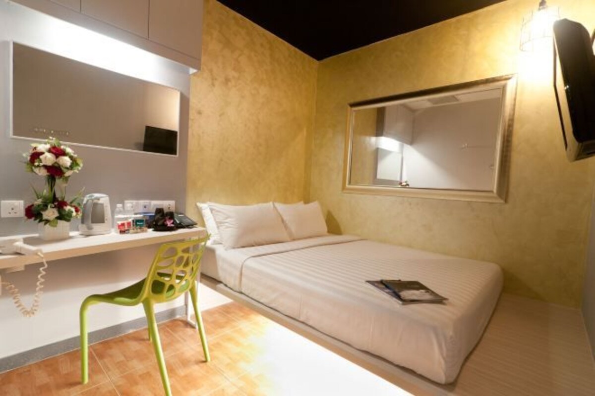 Una habitación de hotel con cama, escritorio, silla, espejo y ventana.