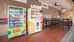 A vending machine area with a colorful drink dispenser and a juice vending machine. - Fragrance Hotel - Rose (Singapore)
