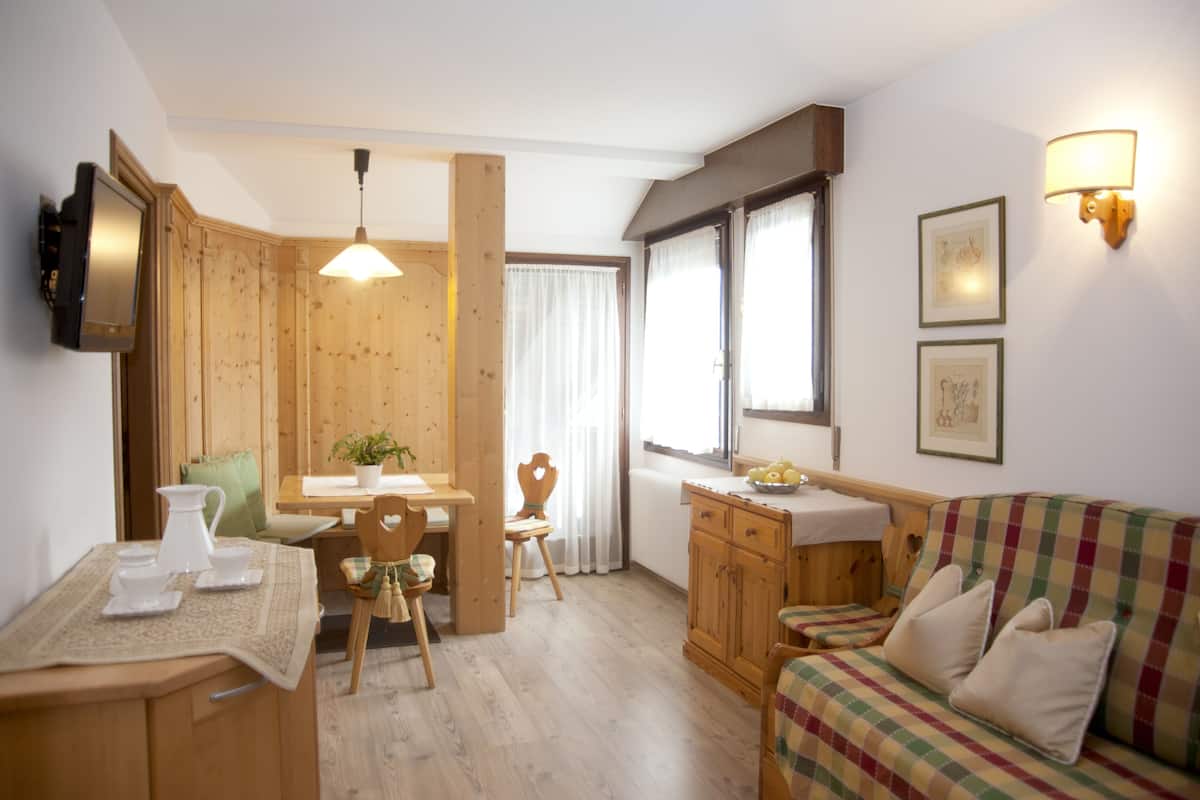 Une pièce chaleureuse avec une table à manger en bois, des chaises, un canapé et un petit coin cuisine.