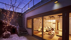 A modern building with a glass entrance leading to a room with a swing chair and a bed.