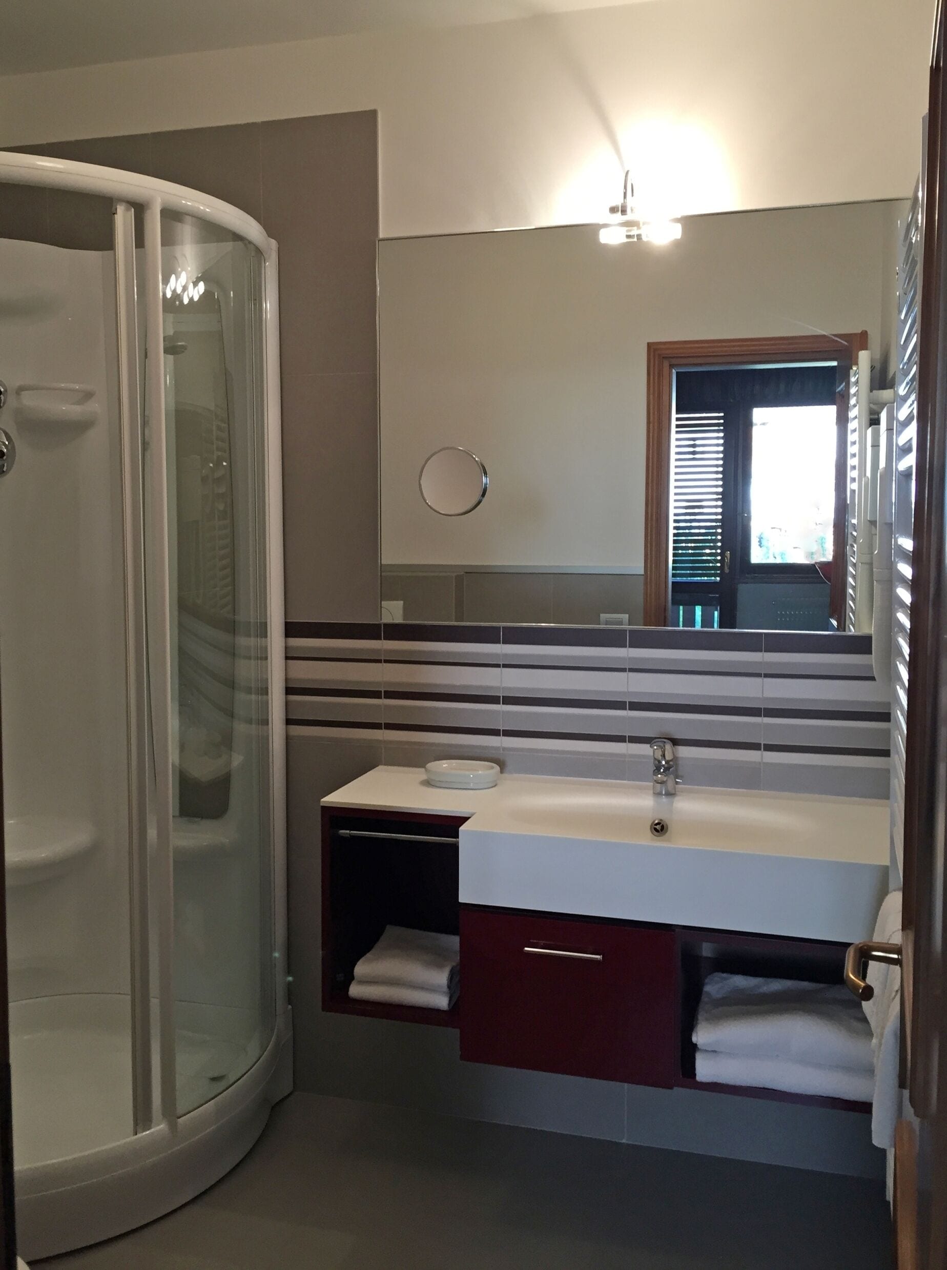 Un baño moderno con cabina de ducha de vidrio, un lavamanos con tocador y un espejo sobre el lavamanos.