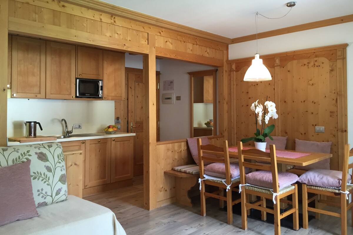 Un intérieur chaleureux en bois, comprenant une cuisine, un coin repas et un lit.