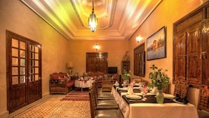 A traditional dining room with a long table set for a meal, wooden furniture, and a chandelier. - Villa Dar Mya Palmiers (Marrakech)